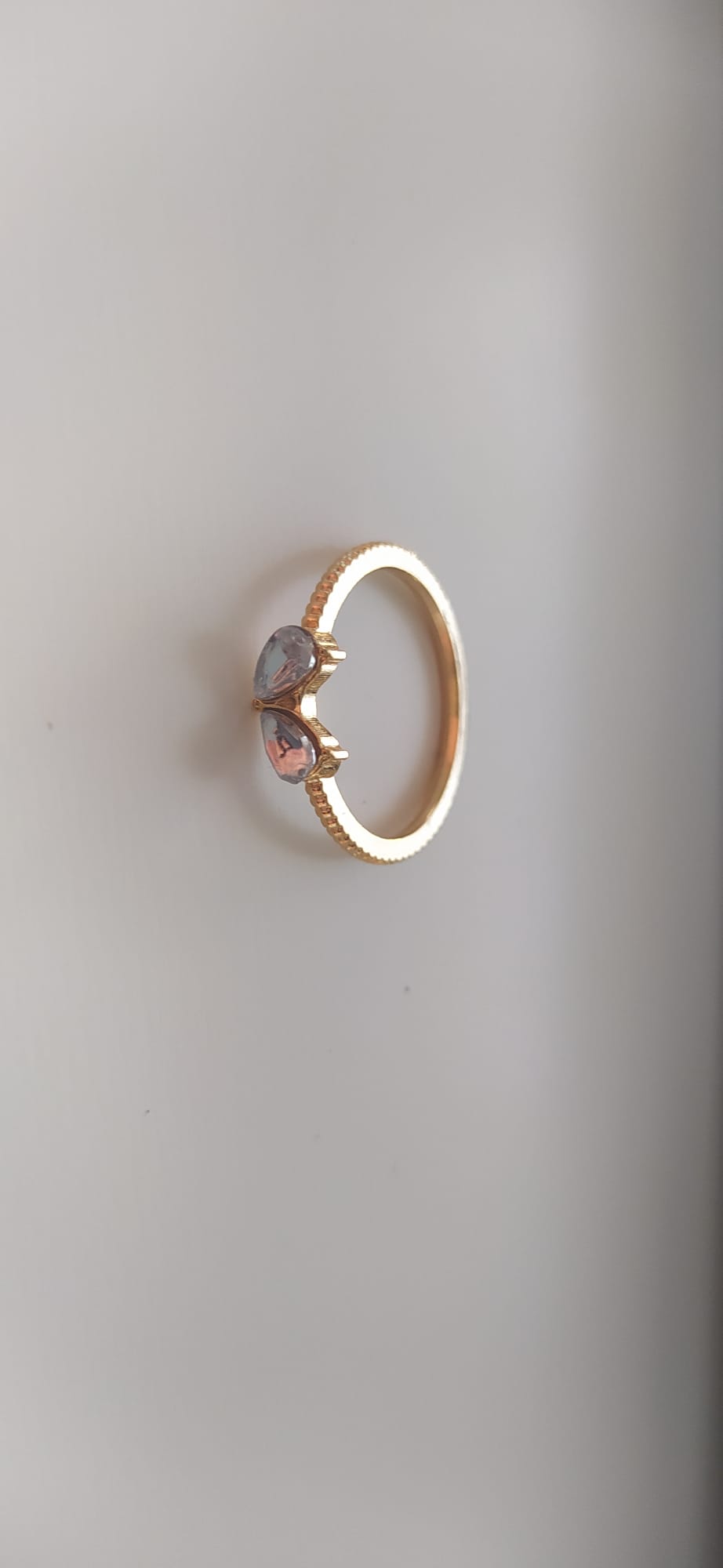 Anillo dorado con dos piedras lila y rosa engarzadas