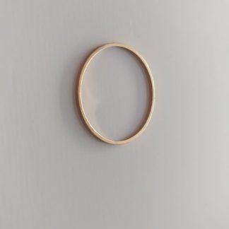 Anillo dorado liso y fino sobre fondo claro