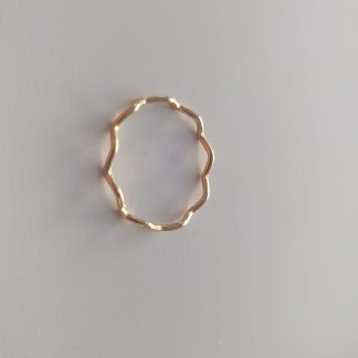 Anillo dorado ondulado con acabado martillado sobre fondo claro
