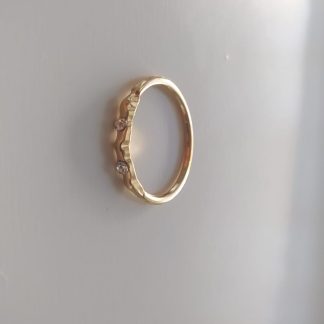 Anillo dorado ondulado con dos circonitas engastadas