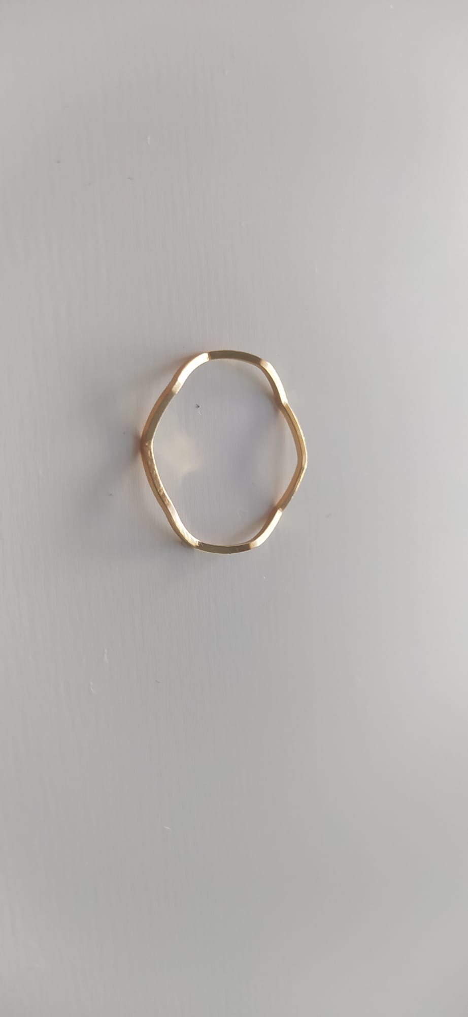 Anillo dorado ondulado de líneas irregulares sobre fondo claro