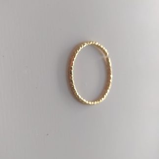 Anillo dorado con textura martillada sobre fondo claro