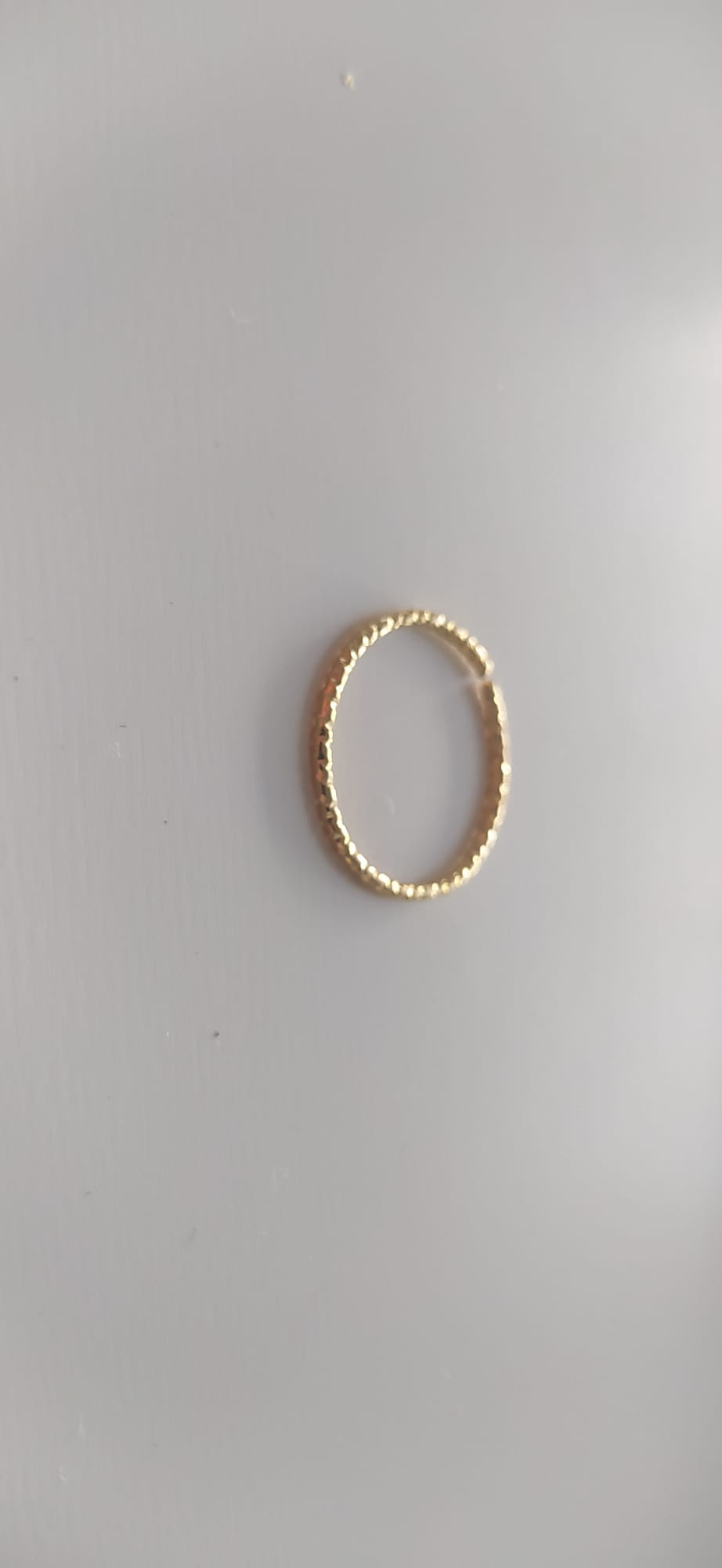 Anillo dorado con textura martillada sobre fondo claro
