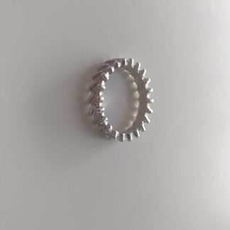 Anillo plateado con fila de bolitas alrededor de la banda sobre fondo claro