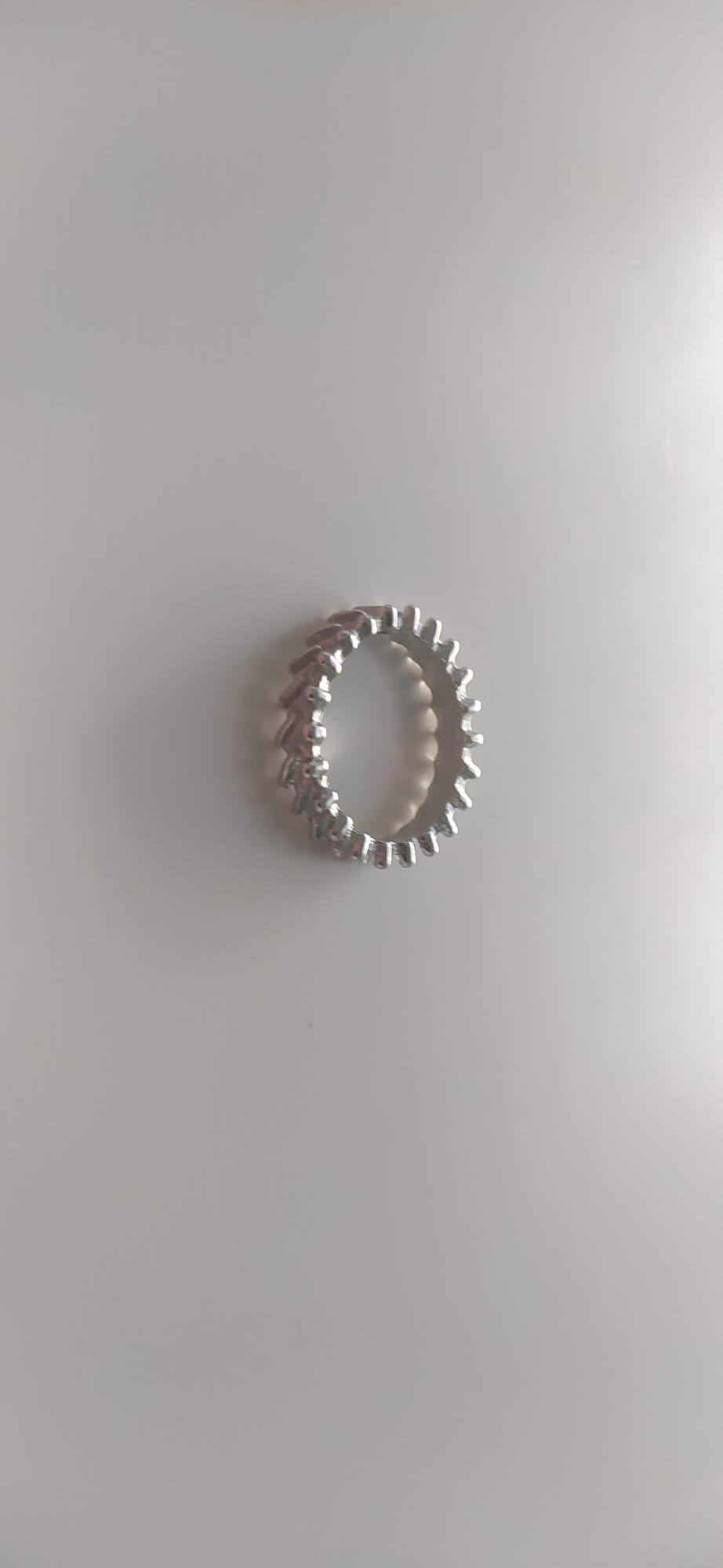 Anillo plateado con fila de bolitas alrededor de la banda sobre fondo claro