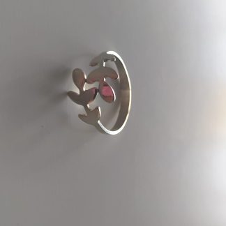 Anillo plateado con diseño calado de hojas y ramita sobre fondo claro