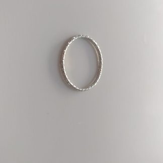 Anillo plateado fino con textura rayada tipo eternity sobre fondo claro