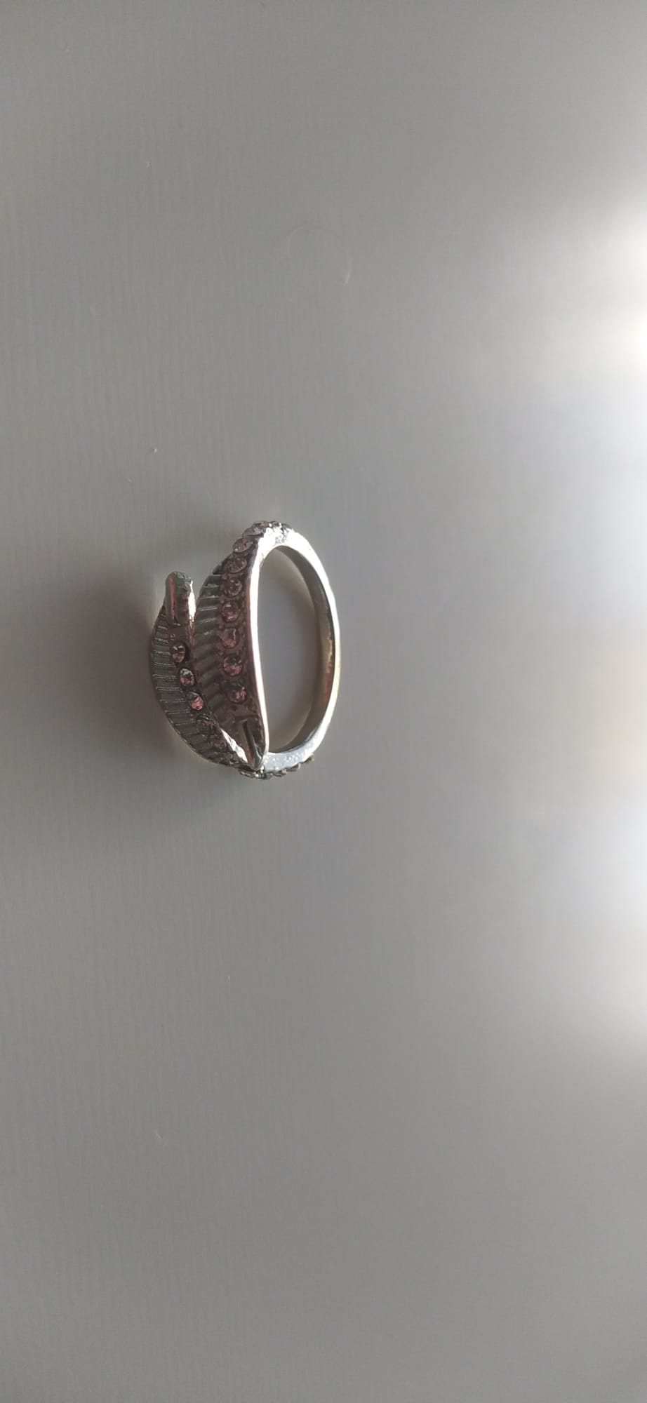 Anillo plateado de bisutería con hoja de circonitas rosas