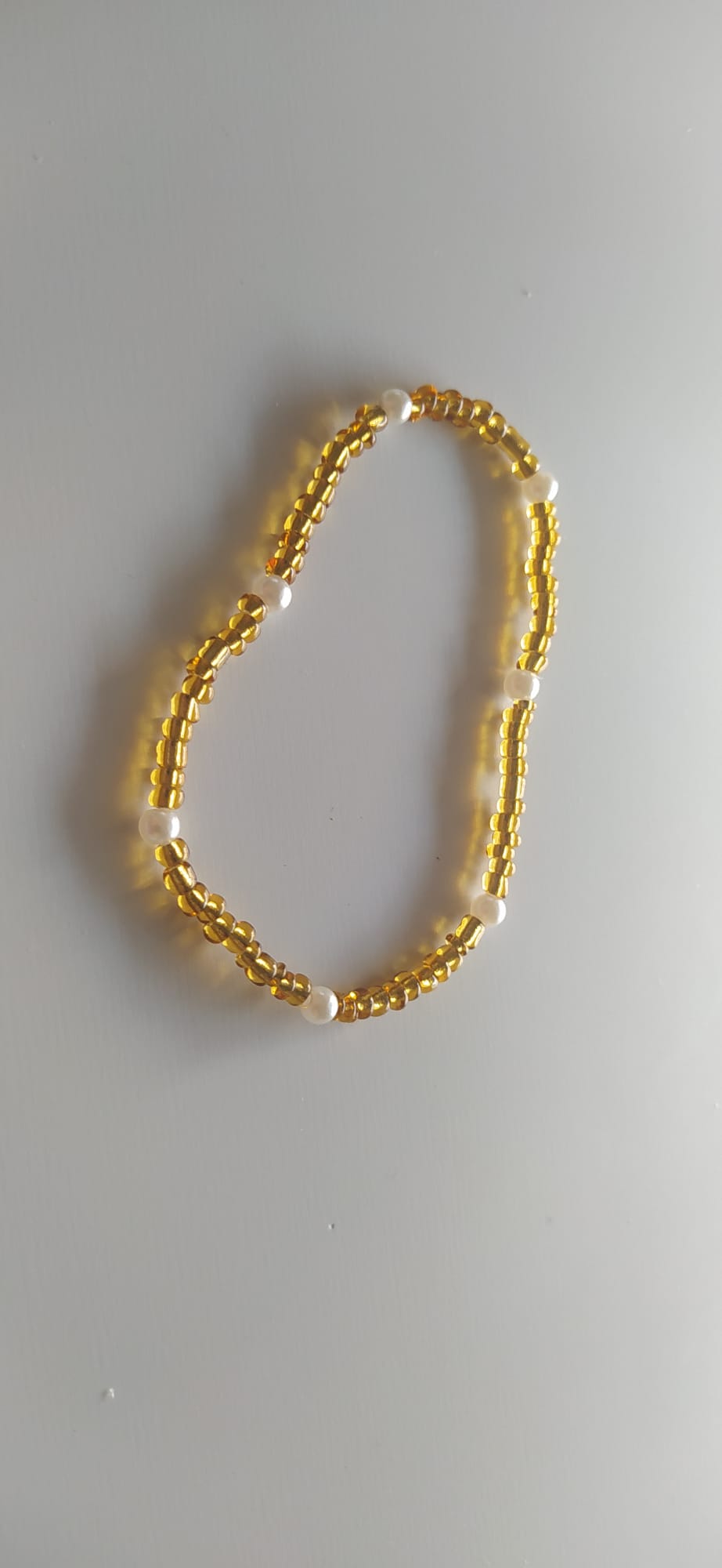 Collar dorado de abalorios tubulares con perlas blancas