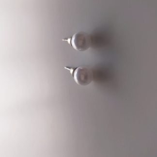 Pendientes de botón con perla blanca sobre superficie clara