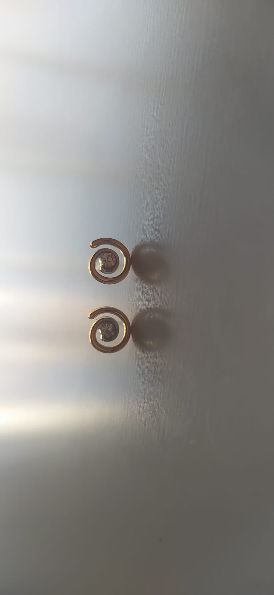 Pendientes dorados en espiral con piedra brillante en el centro