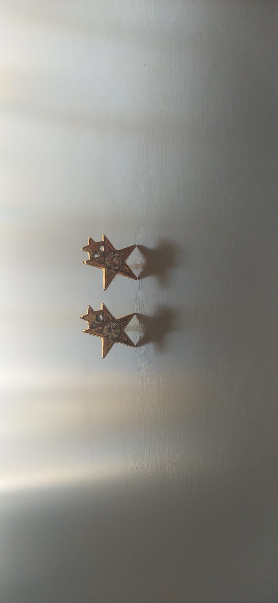 Pendientes de bisutería en forma de estrella dorada con circonita central