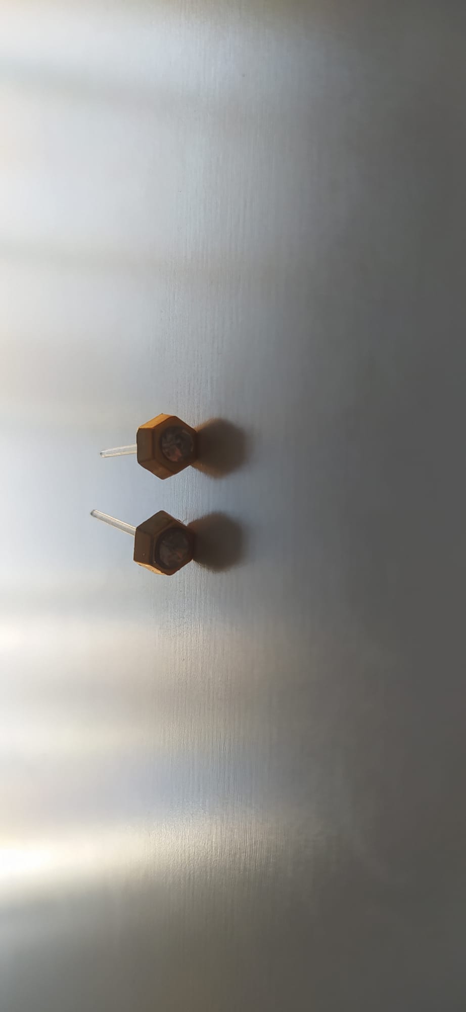 Pendientes dorados hexagonales con piedra ahumada en el centro