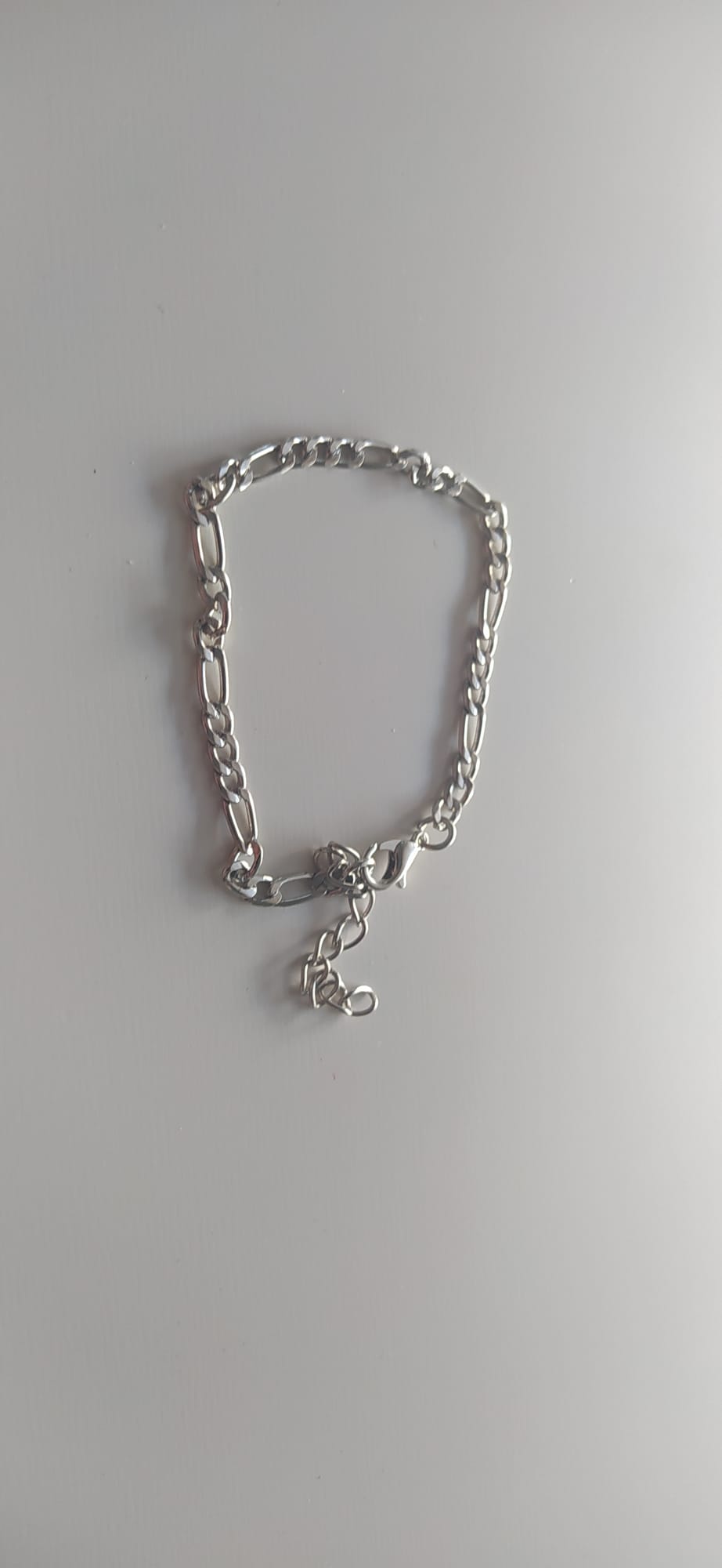 Pulsera de cadena plateada con eslabones estilo Figaro sobre fondo claro