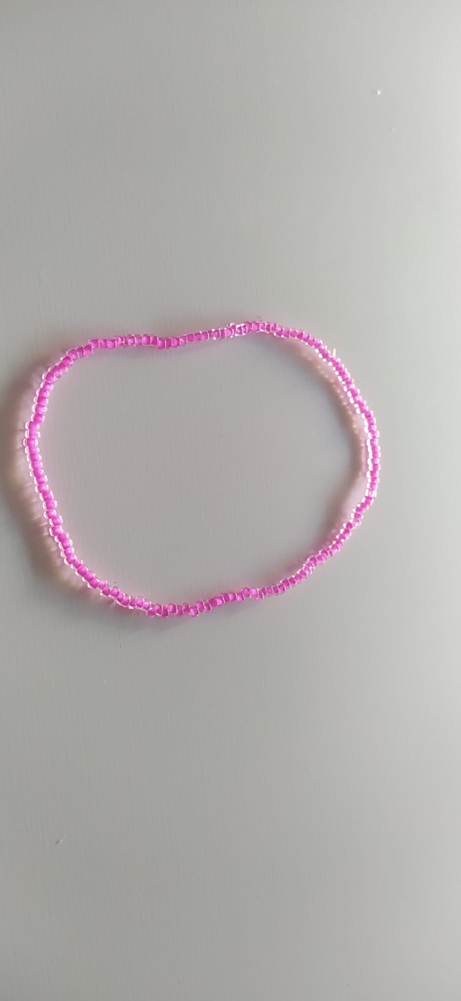 Pulsera de abalorios dorados brillantes sobre superficie clara