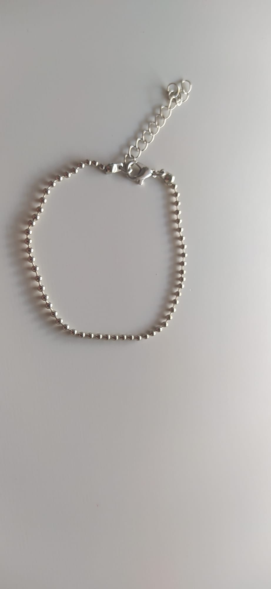 Pulsera de bolitas plateadas con cierre de mosquetón sobre fondo claro