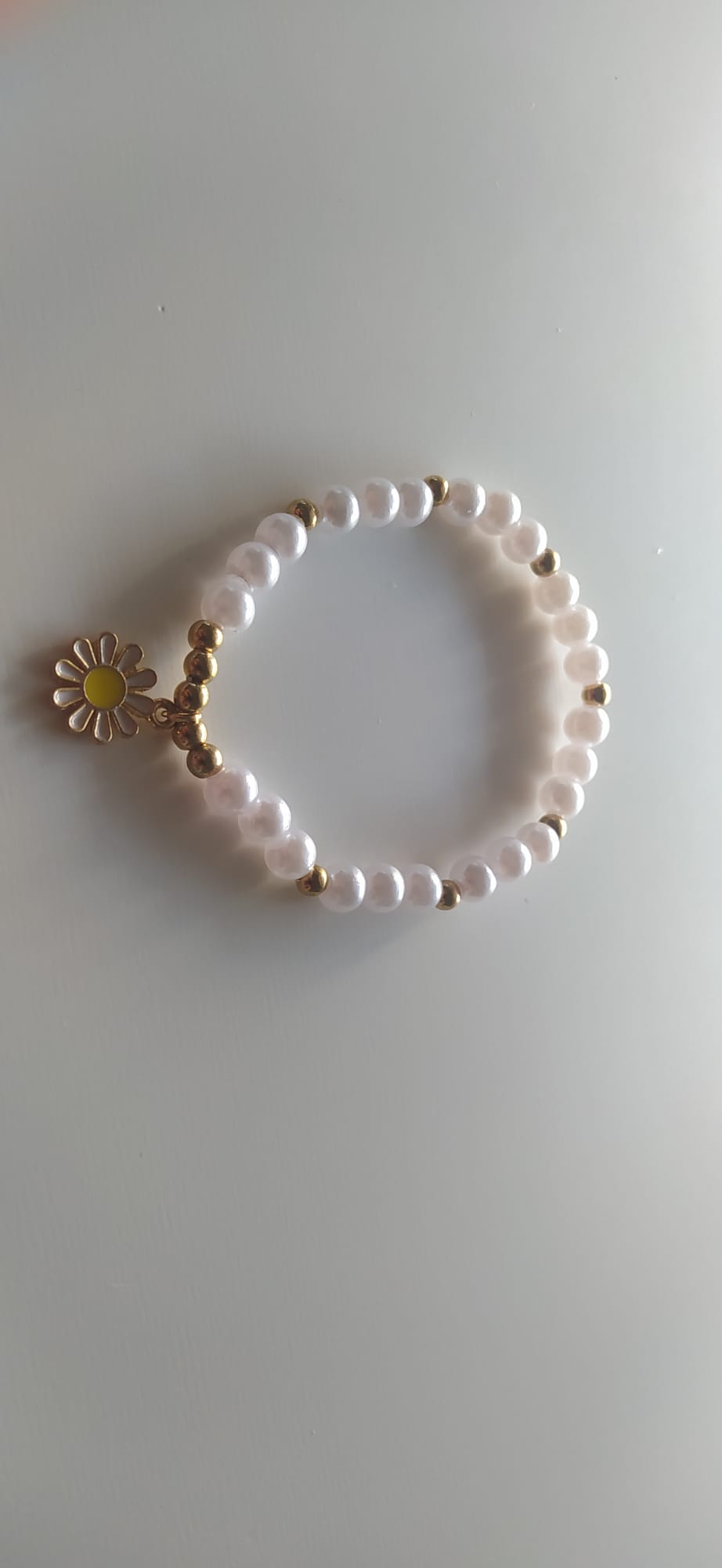 Pulsera artesanal de perlas blancas con dije de margarita dorada y amarilla