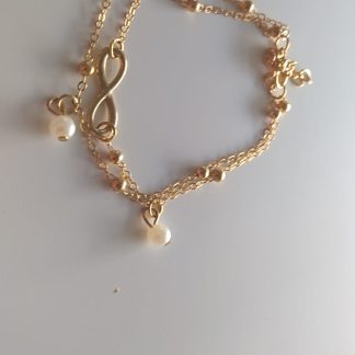 Pulsera dorada de doble cadena con perlas blancas, dije de infinito y corazón