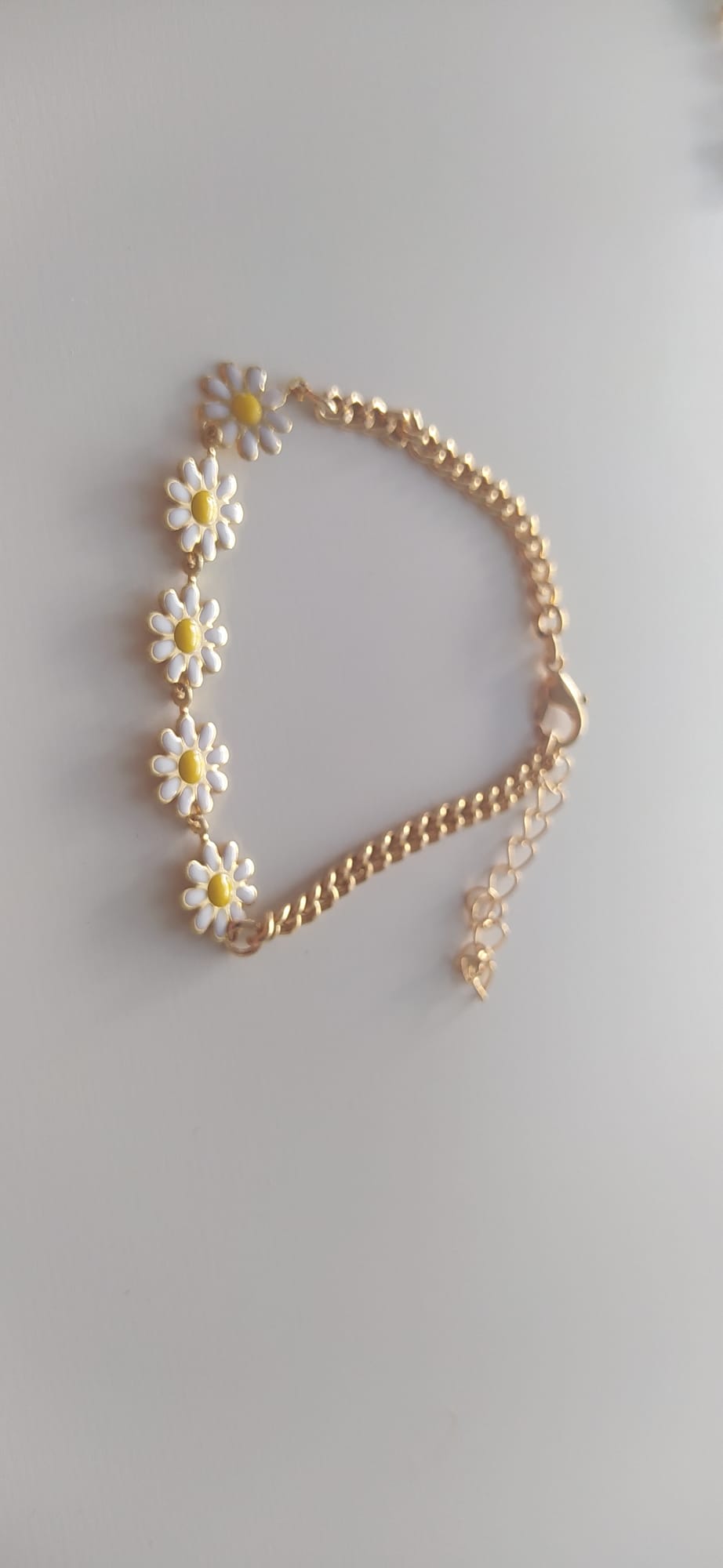 Pulsera dorada con flores de margarita blancas y amarillas