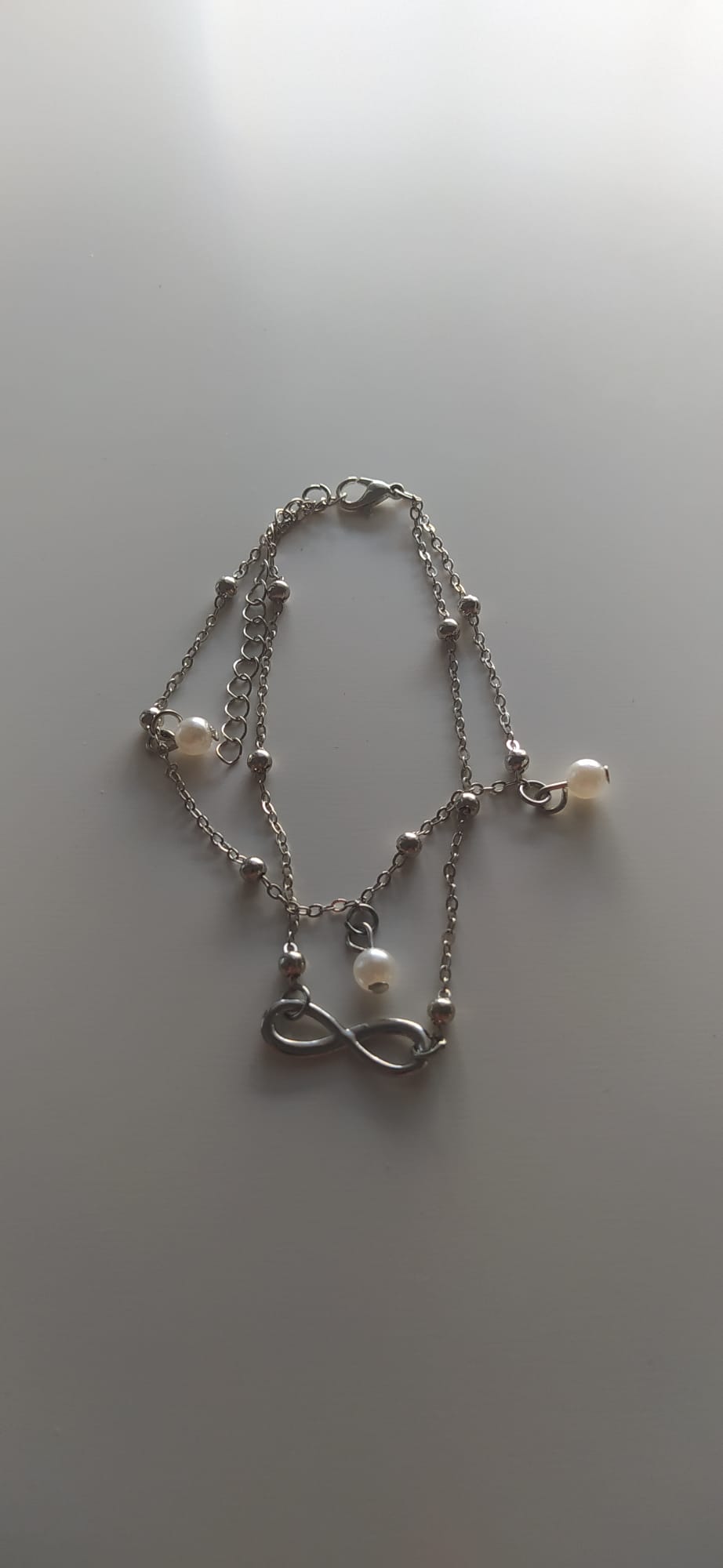 Pulsera plateada de varios hilos con perlas y colgante de infinito