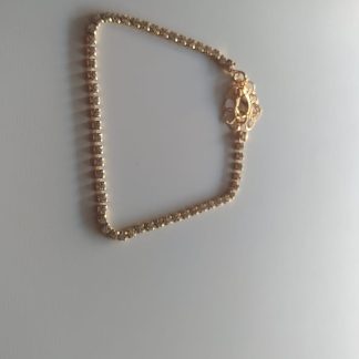 Pulsera dorada tipo tenis con circonitas brillantes y cierre decorativo