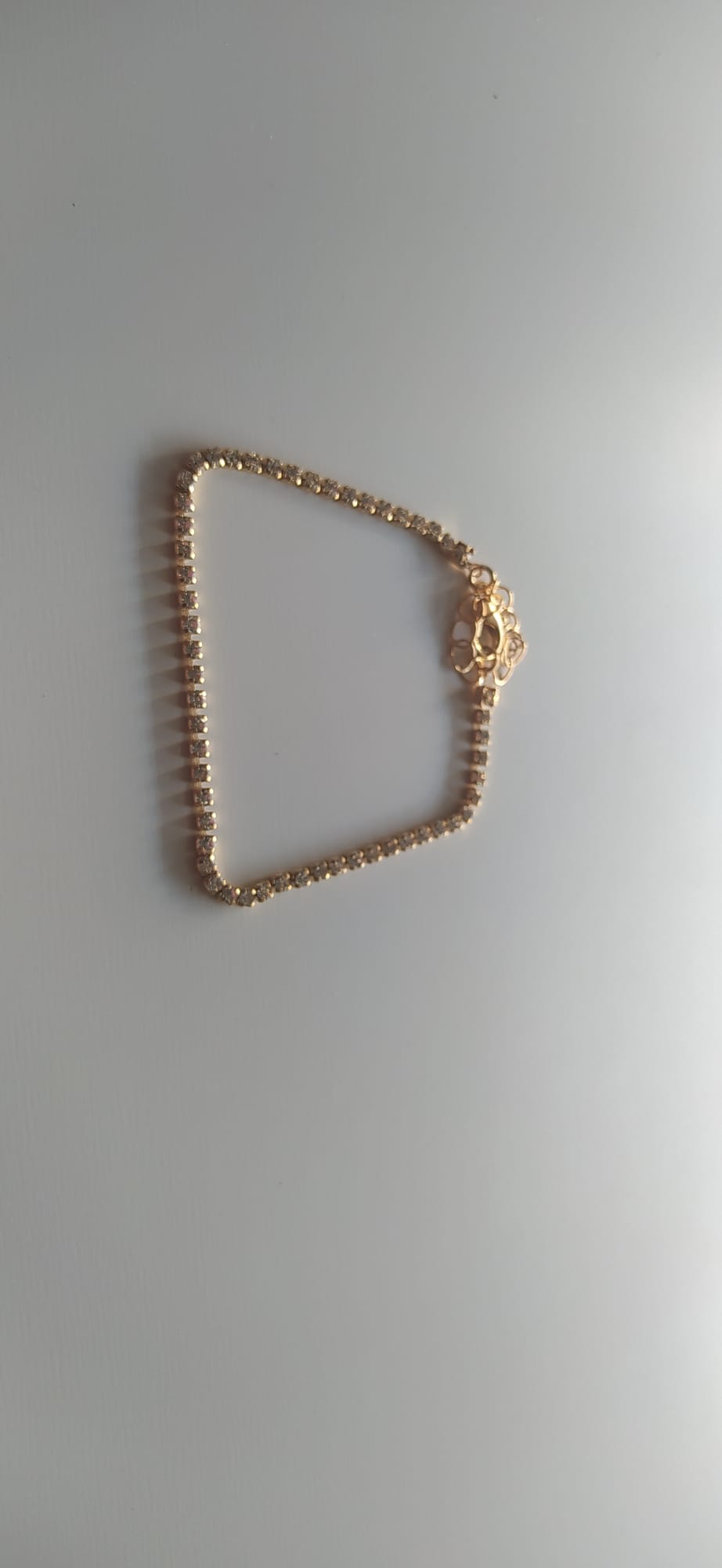 Pulsera dorada tipo tenis con circonitas brillantes y cierre decorativo